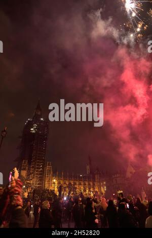 Londra, Regno Unito. 05 novembre 2021. I fuochi d'artificio scendono al Parlamento durante la celebrazione annuale della notte Guy Fawkes. La notte Guy Fawkes è una celebrazione annuale in memoria del Gunpowder Plot, un tentativo di bruciare il Parlamento a Londra il 5 novembre 1605. La protesta è stata tenuta dal gruppo hacktivist anti-establishment Anonymous. I dimostranti sono visti che settano fuochi d'artificio e bombe a gas fuori dal Parlamento mentre indossano la maschera Guy Fawkes. Credit: SOPA Images Limited/Alamy Live News Foto Stock