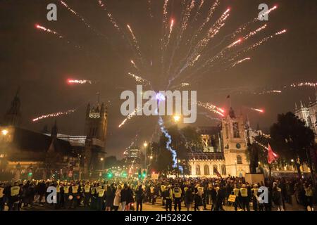 Londra, Regno Unito. 05 novembre 2021. I fuochi d'artificio scendono al Parlamento durante la celebrazione annuale della notte Guy Fawkes. La notte Guy Fawkes è una celebrazione annuale in memoria del Gunpowder Plot, un tentativo di bruciare il Parlamento a Londra il 5 novembre 1605. La protesta è stata tenuta dal gruppo hacktivist anti-establishment Anonymous. I dimostranti sono visti che settano fuochi d'artificio e bombe a gas fuori dal Parlamento mentre indossano la maschera Guy Fawkes. Credit: SOPA Images Limited/Alamy Live News Foto Stock