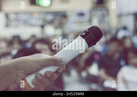 Nel focus selettivo del microfono sopra l'astratto offuscò la foto del seminario di riunione del pubblico nella stanza di conferenza sfondo. Foto Stock