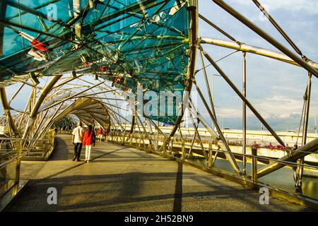 Tour turistico o locale a piedi attraverso il ponte Helix a Marina Bay durante il tramonto. Foto Stock