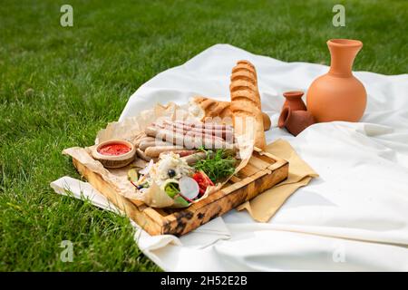 salsicce grigliate fatte in casa con verdure e vino in un picnic. Foto Stock