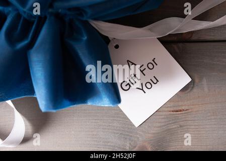 sacco da regalo blu con carta di testo su sfondo di legno Foto Stock