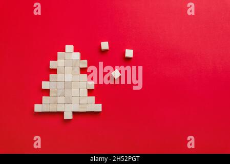 Albero di Natale fatto di cubi di legno su un tavolo rosso con spazio libero per il testo di saluto di Natale. Vista dall'alto, composizione di giacitura piatta Foto Stock