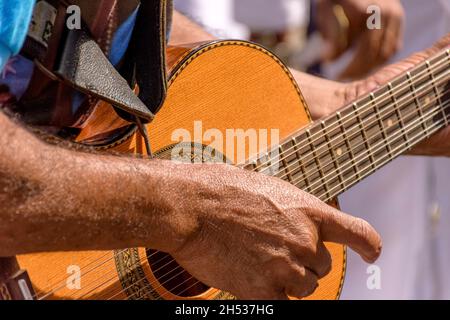 Dettaglio delle mani del chitarrista e della sua chitarra acustica in una popolare presentazione musicale all'aperto Foto Stock
