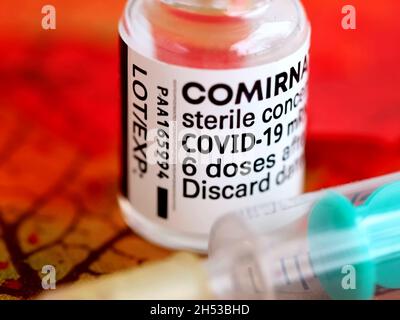 Comirrnaty Biontech Pfizer fiala di vaccinazione con una siringa contro il virus covid-19 o Corona su foglietti rossi Foto Stock