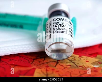 Comirrnaty Biontech Pfizer fiala di vaccinazione con una siringa contro il virus covid-19 o Corona su foglietti rossi Foto Stock