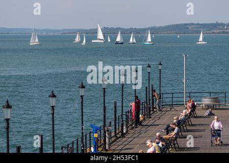 Yacht fuori in numeri nel Thames Estuary con la gente fuori godere il molo in un luminoso giorno di settembre soleggiato Foto Stock