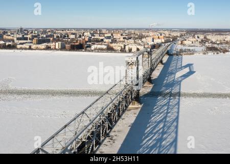 Arkhangelsk, Russia - 11 marzo 2021:la vista dall'alto in inverno sul ponte di ferro e una città attraverso il fiume ghiacciato. Foto Stock
