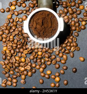 Caffè macinato in un corno tra i chicchi aromatici. Concetto domestico di preparazione del caffè. Orientamento orizzontale. Vista dall'alto. Primo piano. Foto Stock