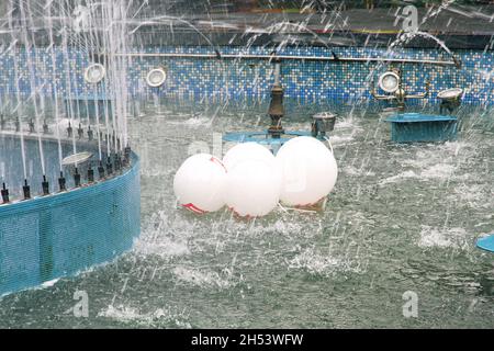 molti palloncini bianchi con un motivo rosso galleggiano nella fontana dopo la festa. ha lasciato cadere le palle nella fontana Foto Stock