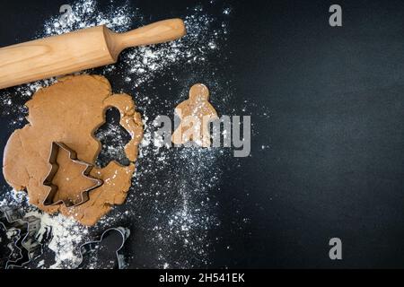 Le mani dei bambini fanno i biscotti del pan di zenzero di Capodanno su un tavolo di legno. Capodanno e Natale. Foto Stock