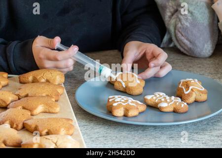 Le mani dei bambini fanno i biscotti del pan di zenzero di Capodanno su un tavolo di legno. Capodanno e Natale. Foto Stock