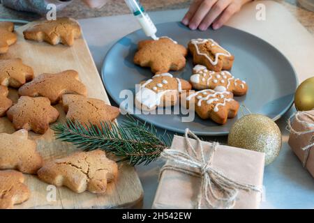 Le mani dei bambini fanno i biscotti del pan di zenzero di Capodanno su un tavolo di legno. Capodanno e Natale. Foto Stock