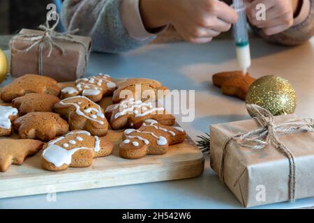 Le mani dei bambini fanno i biscotti del pan di zenzero di Capodanno su un tavolo di legno. Capodanno e Natale. Foto Stock