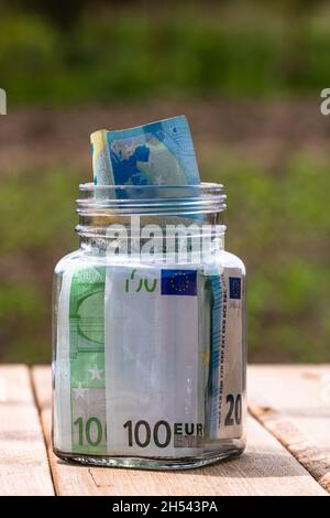 Composizione con banconote in denaro risparmiate in un vaso di vetro Foto Stock