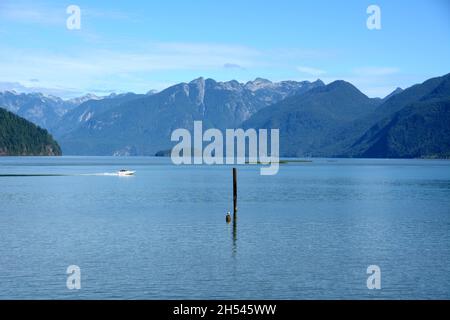 Un motoscafo sul lago Pitt, uno dei più grandi laghi di marea del mondo, e sulle montagne della catena Garibaldi, Pitt Meadows, British Columbia, Canada. Foto Stock