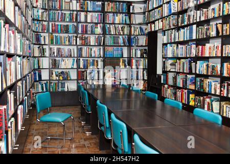 Molti libri colorati che giacciono sugli scaffali nella sala di lettura della biblioteca Foto Stock