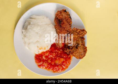 Tradizionale pasto africano di mais pap di cibo di base, pollo fritto e salsa di pomodoro Foto Stock