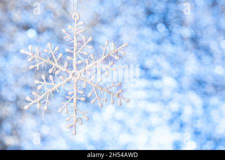 fiocco di neve bianco su sfondo bianco-blu lucido sfocato. Spazio di copia. Modello per la progettazione Foto Stock