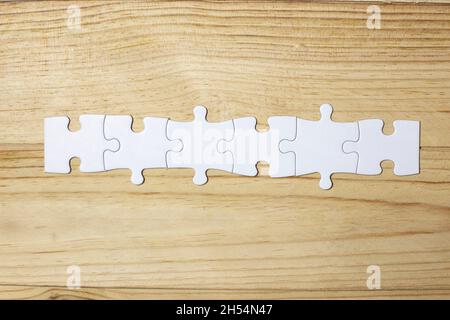 Sei pezzi bianchi di un puzzle su sfondo di legno. Spazio di copia. Concetto di Unione. Spazio per lettere e testo. Foto Stock