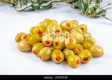 Piccole olive verdi in salamoia, farcite con peperoncino rosso in una ciotola di legno. Frutta di Olea europaea, farcita con fette di peperone. Primo piano da abov Foto Stock