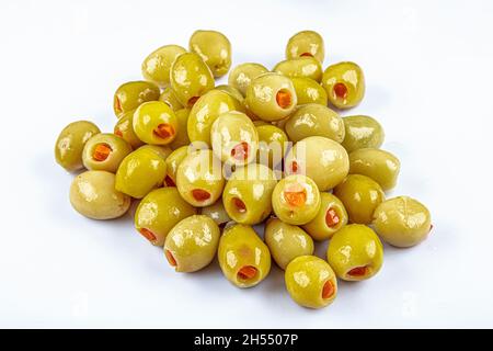 Piccole olive verdi in salamoia, farcite con peperoncino rosso in una ciotola di legno. Frutta di Olea europaea, farcita con fette di peperone. Primo piano da abov Foto Stock