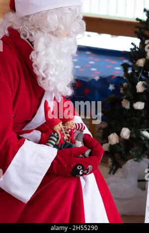 Babbo Natale con giocattoli che giocano per i bambini. Spirito di vacanza e intrattenimento natalizio per bambini. Foto Stock