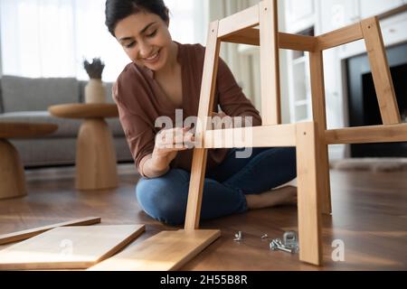 La donna indiana raccoglie mobili in legno seduti sul pavimento di casa Foto Stock