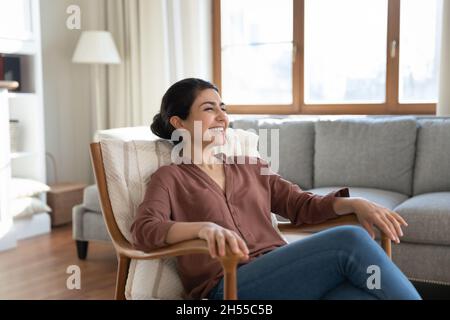 Donna indiana che si rilassa su una comoda poltrona in un accogliente soggiorno Foto Stock