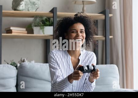 Ridendo afroamericana donna che gioca video gioco, seduto sul divano Foto Stock