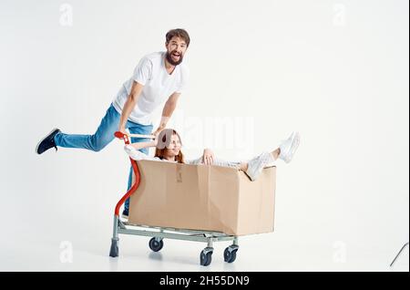 una giovane coppia cavalcare un carrello intrattenimento sfondo chiaro Foto Stock