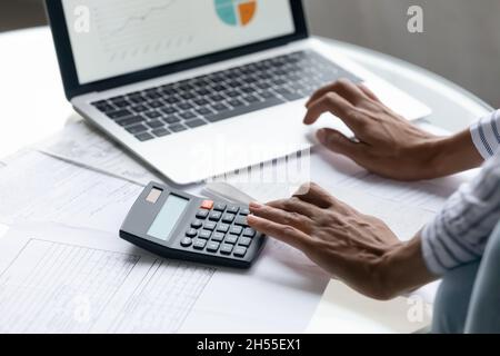 Primo piano ritagliato donna afroamericana calcolando le fatture, utilizzando il portatile Foto Stock