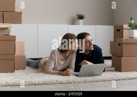 Coppia sognante che si diverse a vivere una giornata in movimento, utilizzando un notebook in una nuova casa Foto Stock