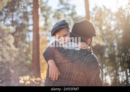 Il giorno del Padre. Triste figlio che abbraccia papà sullo sfondo della foresta con spazio copia. Concetto di relazione padre-figlio Foto Stock