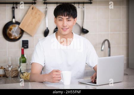 Giovane uomo che utilizza un computer portatile a casa Foto Stock