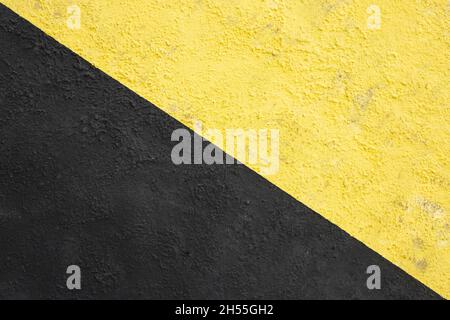 Parete dipinta di giallo e nero. Divisa in due parti da una linea verticale. Sfondo urbano. Spazio copia. Stile industriale. Foto Stock