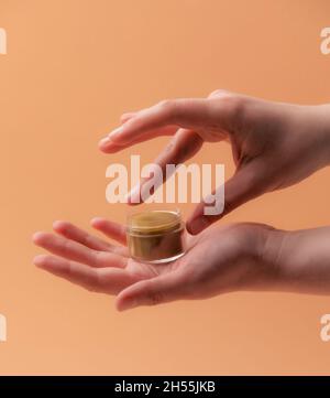 Balsamo naturale eco labbro con le mani femminili su beige Foto Stock