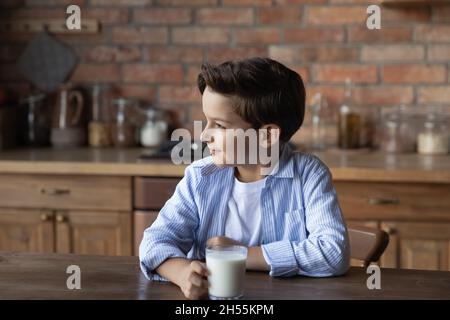 Carino bambino presteen sedersi al tavolo tenere un bicchiere di latte Foto Stock