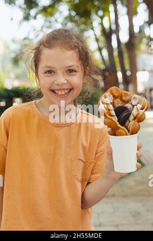 La bambina sta gustando un waffle belga Foto Stock