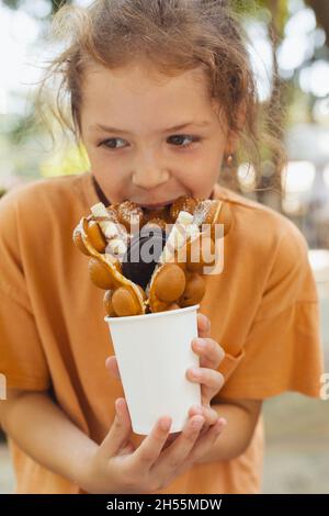 La bambina sta gustando un waffle belga Foto Stock