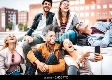 Amici allegri che si divertono con il telefono cellulare presso il campus universitario - ragazzi e ragazze gioiosi che trascorrono tempo tecnologico insieme Foto Stock