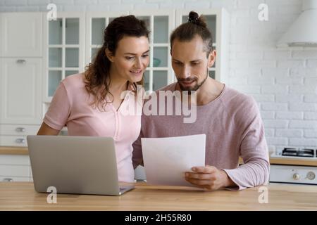 Felice coppia di famiglia lettura lettera di carta in cucina. Foto Stock