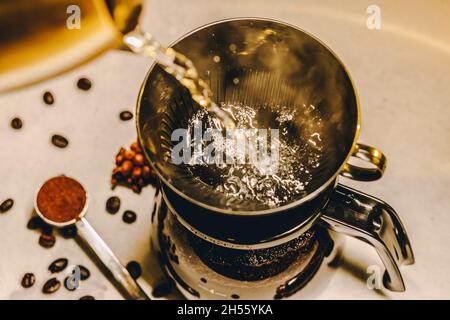 Preparazione del caffè con un contagocce. La macchina per caffè in vetro pour-over è estremamente vicina al getto di acqua bollente Foto Stock