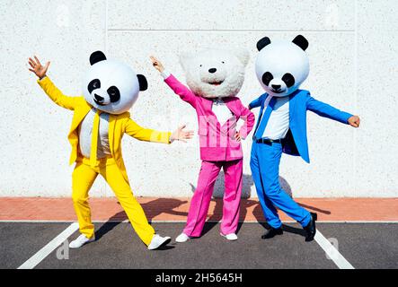 Immagine narrativa di una coppia che indossa una testa panda gigante e abiti colorati. Uomo e donna che fanno festa in un parcheggio. Foto Stock