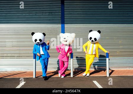 Immagine narrativa di una coppia che indossa una testa panda gigante e abiti colorati. Uomo e donna che fanno festa in un parcheggio. Foto Stock