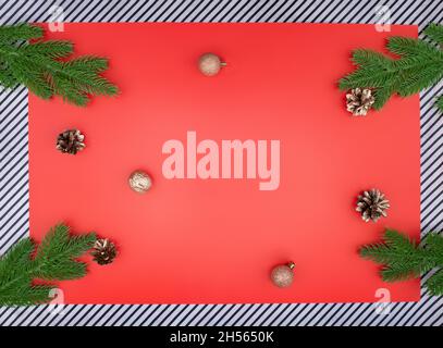 Rami di abete rosso con coni dorati e noci con rami di abete rosso verde su sfondo rosso e strisce. Spazio per la copia di Natale e Capodanno Foto Stock
