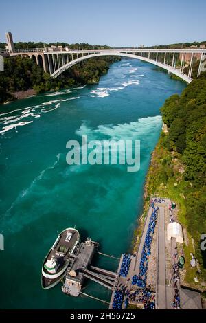 Cascate del Niagara paesaggio mozzafiato con tour barca e turisti in blu impermeabile in attesa in coda sotto | Niagara River con la gente attendere a bordo di una barca Foto Stock