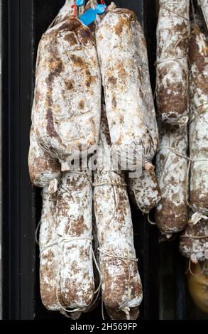 Differenti varietà di salumi appesi a un negozio di gastronomia Foto Stock