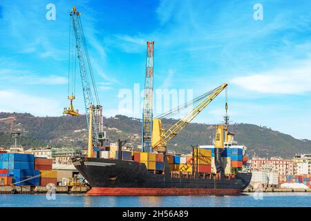 Porto internazionale nel Golfo di la Spezia con una nave container nero e rosso ormeggiato e gru. Liguria, Italia, Europa. Foto Stock