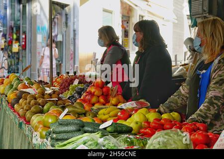 Tre donne con maschere che vendono frutta e verdura in una strada a Granada (Spagna) Foto Stock